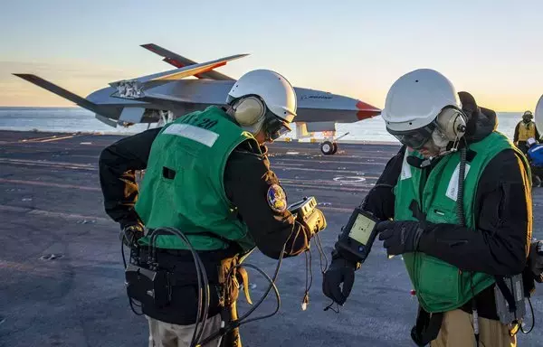 Personnel run diagnostics on the unmanned MQ-25 aircraft on the flight deck aboard the aircraft carrier USS George H.W. Bush in December 2021. [US Navy]