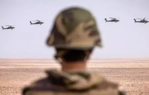 A member of the Moroccan Royal Armed Forces looks on as US army AH-64 Apache attack helicopters fly over during the second annual African Lion military exercise in the Tan-Tan region in southwestern Morocco last June 30. [Fadel Senna/AFP]