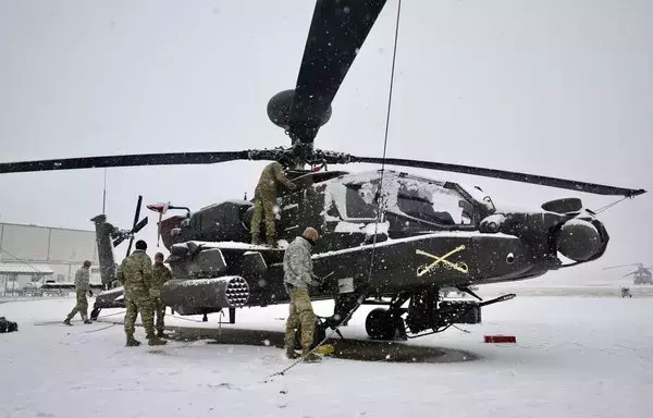 US soldiers move an AH-64E Apache helicopter into a hangar moments after a snowstorm passed through US Army Garrison Humphreys in South Korea last December 6. [US Army]
