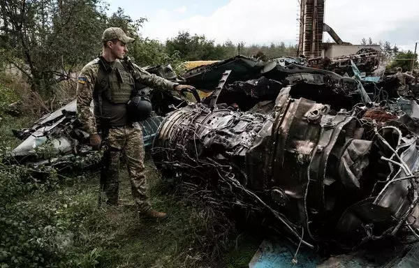 A Ukrainian army press officer shows the debris of a Russian Su-34 at a collection point of destroyed Russian armoured vehicles at an animal feed plant in the recently retaken town of Lyman in Donetsk region, on October 5. [Yasuyoshi Chiba/AFP]