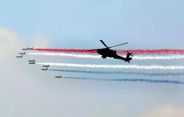Egyptian air force acrobatic jets perform aerial maneuvers with colored smoke as they fly past an Egyptian AH-64 Apache attack helicopter over the capital Cairo on June 2, 2018, during the inauguration of Egyptian President Abdel Fattah al-Sisi for a second four-year term in office. [AFP]