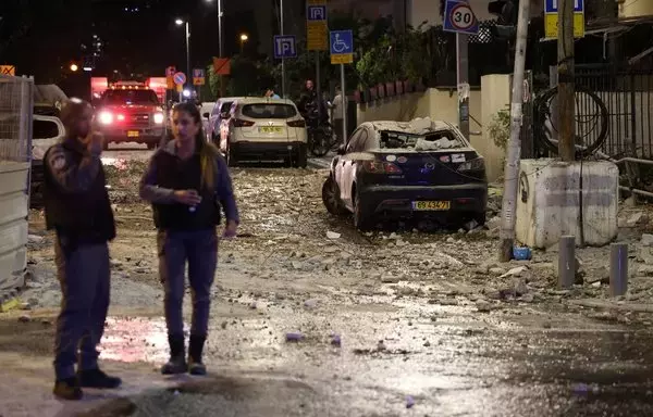 Israeli security forces stand along a debris-strewn street in Tel Aviv, after it was hit by a rocket fired by Palestinian militants from the Gaza Strip on October 7. [Jack Guez/AFP]