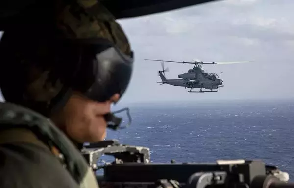A US Marine looks out the side door of the aircraft while flying alongside an AH-1Z Viper to a live-fire range in Okinawa, Japan, November 3. [US Marine Corps]
