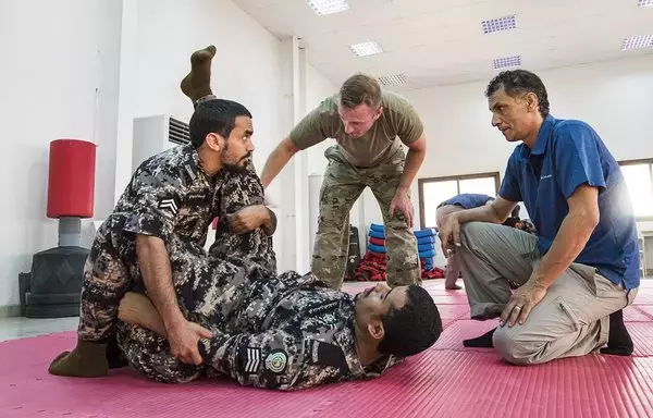 جندي احتياطي بالجيش الأميركي (في الوسط)، يقدم إرشادات حول تقنيات الدفاع عن النفس لاثنين من طلاب قوات الأمن السعودية في موقع تدريب في المملكة العربية السعودية في حزيران/يونيو 2019. [الجيش الأميركي]