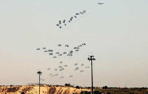 صورة التقطت من الحدود الجنوبية لإسرائيل مع قطاع غزة، تظهر طائرة عسكرية تسقط مساعدات إنسانية بالمظلات فوق غزة يوم 4 نيسان/أبريل. [جاك غويز/وكالة الصحافة الفرنسية]