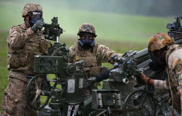 Soldiers prepare a howitzer after a simulated chemical, biological, radiological, nuclear attack during a live-fire exercise in Germany November 9, 2022. [US Army]