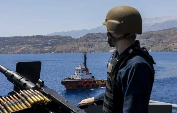 A US Navy sailor assigned to the USS Wasp mans a gun mount as the Wasp pulls into Souda Bay, Greece, July 8. [US Navy]