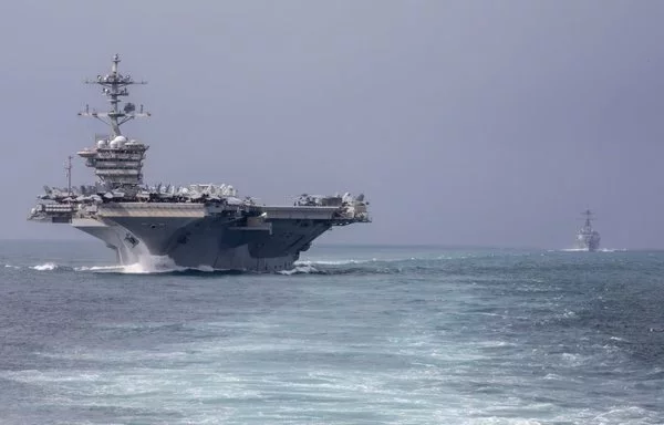 The aircraft carrier USS Abraham Lincoln, left, and the guided-missile destroyer USS Frank J. Petersen Jr. transit the Singapore Strait, August 15. [US Navy]